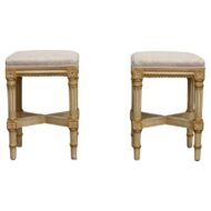 This is a pair of French painted stools in the Louis XVI style, with custom linen upholstery.